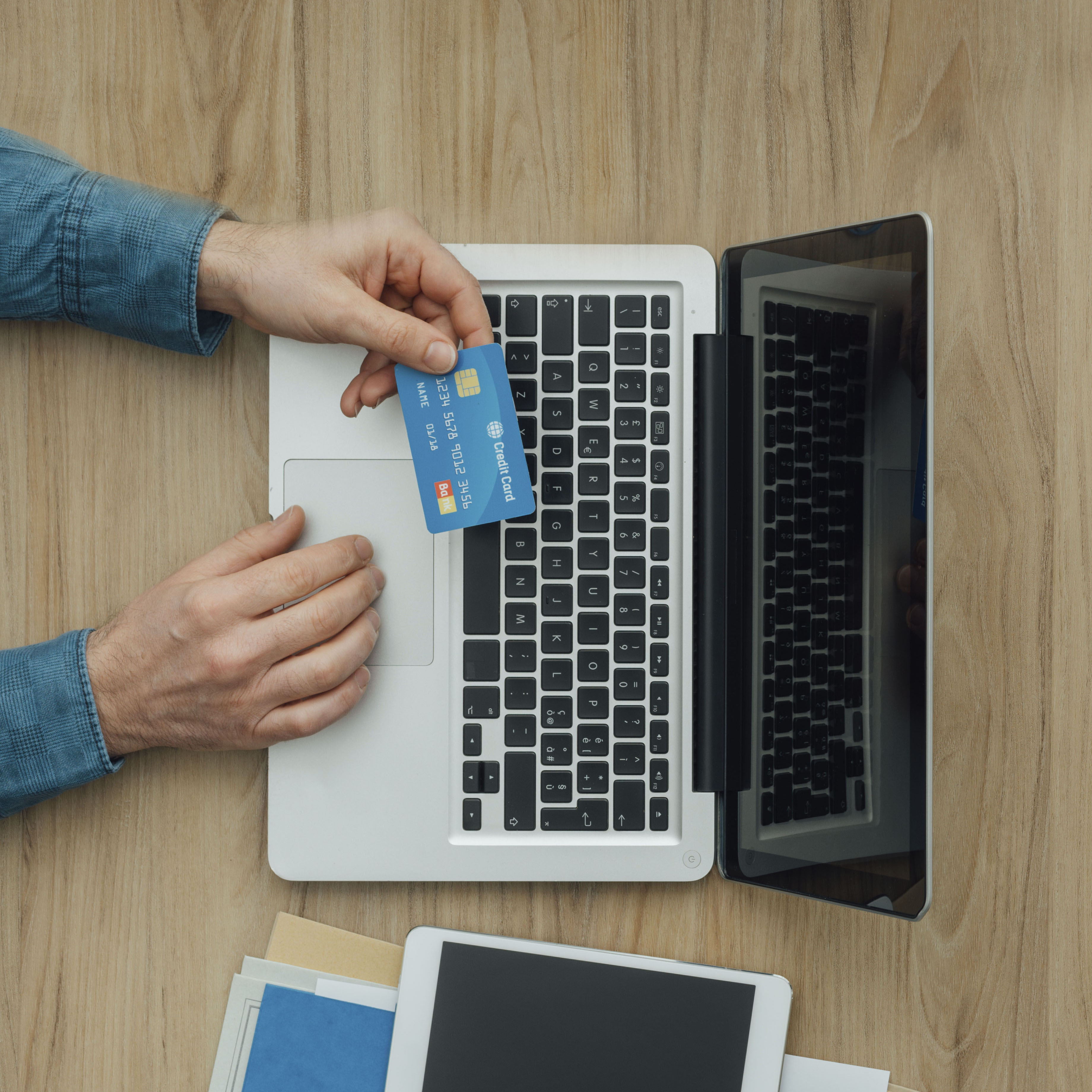 Man working at desk and purchasing products online, he is making a payment using a credit card, online shopping concept